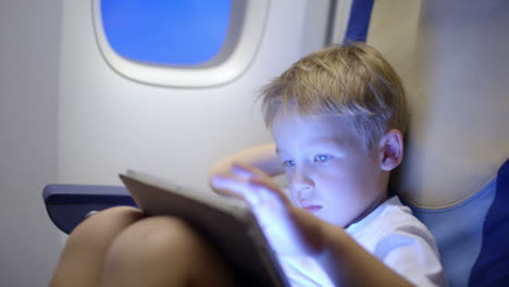 Chico-Aburrido-O-Cansado-En-Avión-Usando-Tablet-PC
