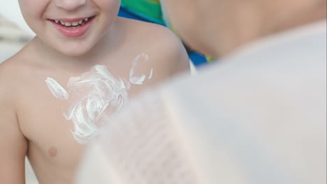 Madre-Dibujando-Sol-En-El-Pecho-De-Su-Hijo-Con-Crema-Solar