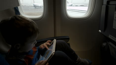 Niño-Sentado-En-El-Avión-Y-Usando-Tablet-Pc