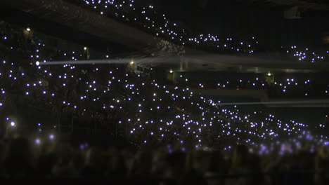 Crowd-on-stands-waving-flashlights-at-night