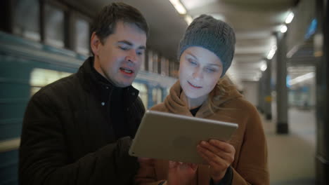 Young-people-discussing-something-using-pad-at-metro-station