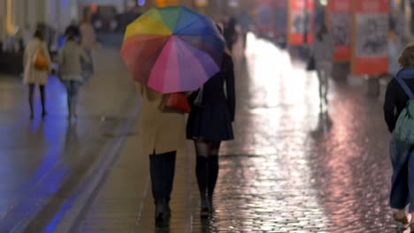 City-walk-under-colorful-umbrella-in-rainy-evening
