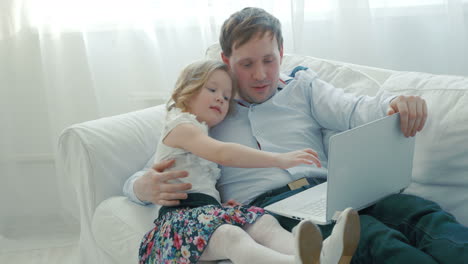 Father-and-daughter-using-laptop-on-the-sofa