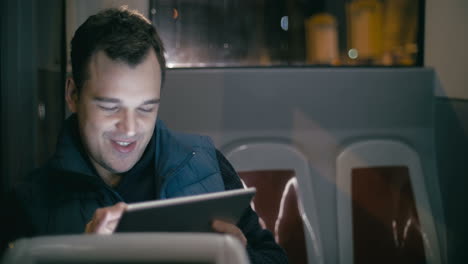 Smiling-man-in-the-bus-with-tablet-computer