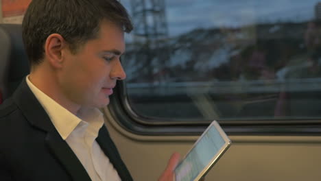 Man-in-Train-Laughing-at-Tablet