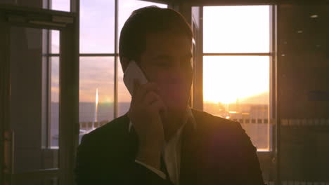 Man-in-the-airport-having-a-phone-talk-at-sunset