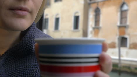 Mujer-Bebiendo-Té-Junto-A-La-Ventana-Con-Vistas-A-Venecia.