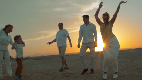 Big-happy-family-dancing-on-the-beach-at-sunset