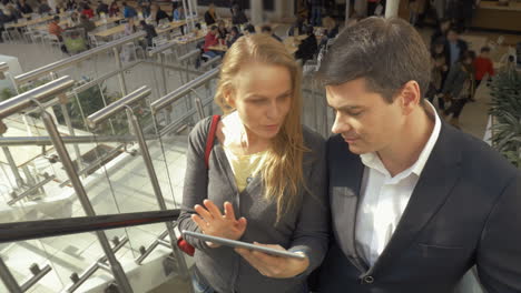 Businesspeople-using-pad-on-escalator