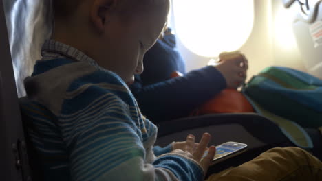 Niño-Pequeño-En-Avión-Usando-Teléfono-Inteligente