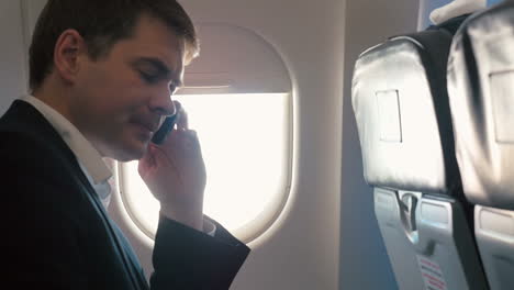 Young-man-having-a-business-phone-talk-in-plane