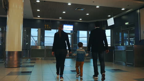 Family-of-three-walking-in-airport-terminal