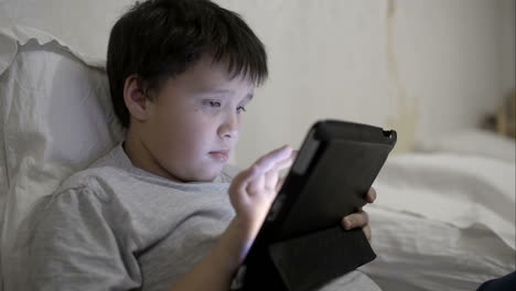 Teenager-Junge-Benutzt-Tablet-Computer-Im-Bett-Liegend
