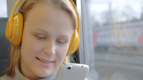 Mujer-Usando-Celular-Y-Escuchando-Música-En-El-Tren.