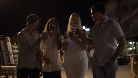 Friends-toasting-with-coffee-cups-in-night-street