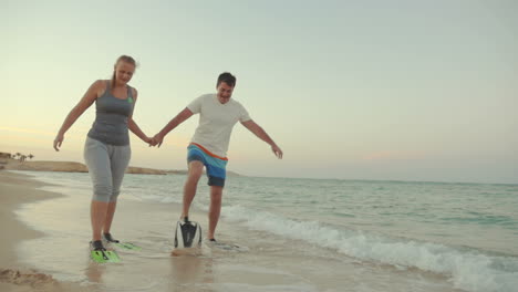 Couple-in-flippers-walking-clumsy-along-the-shore