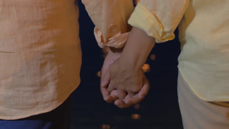 Senior-couple-holding-hands-by-the-sea-at-night