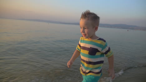 Happy-boy-running-on-the-sea-coast-at-sunset