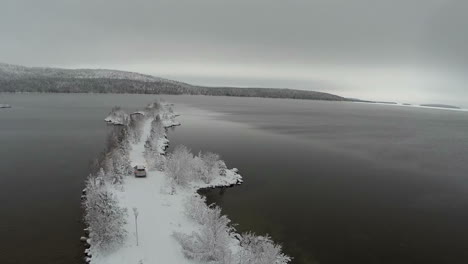 Car-driving-on-winter-island-road-in-the-river-aerial-view