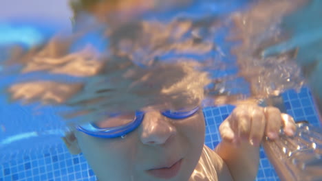 Child-wearing-goggles-diving-in-the-pool