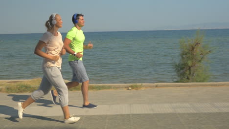 Hombre-Y-Mujer-Corriendo-Sobre-El-Pavimento-Junto-Al-Mar