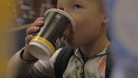 Blick-Auf-Einen-Kleinen-Jungen,-Der-Aus-Dem-Pappbecher-Trinkt,-Und-Ein-Lächelndes-Fast-Food-Café