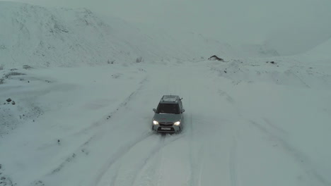 Coche-En-Carretera-Cubierta-De-Nieve-En-Las-Montañas-A-Vista-De-Pájaro.