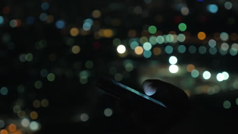Woman-with-mobile-phone-against-night-blurred-cityscape