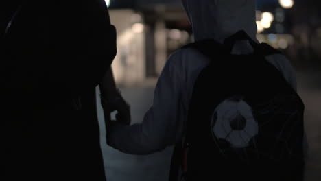 Child-and-mother-holding-hands-while-walking-at-night