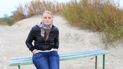 Young-girl-is-sitting-on-a-bench-near-the-sea