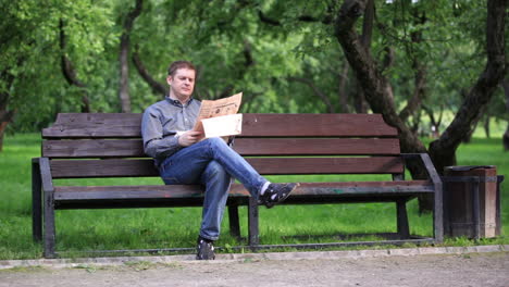 Man-reads-newspaper-on-bench-in-the-park-1