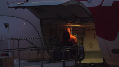Airport-worker-unloading-aircraft-at-night