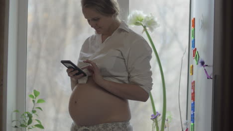 Lächelnde-Schwangere-Frau-Mit-Mobiltelefon-Zu-Hause