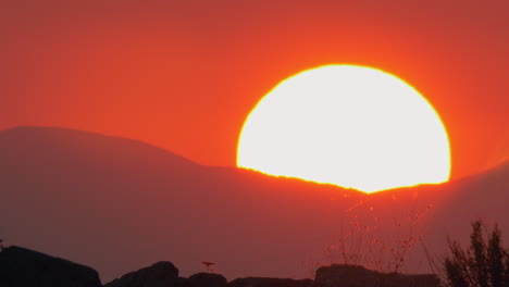 Szene-Mit-Rotem-Himmel-Und-Sonne,-Die-Sich-Hinter-Den-Bergen-Versteckt