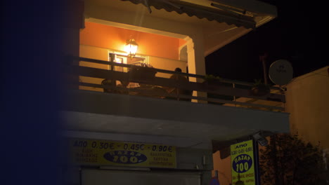 Nachtansicht-Des-Hauses-Mit-Familie-Auf-Dem-Balkon-Griechenland