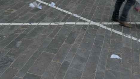 People-feet-walking-in-the-street-with-paper-litter