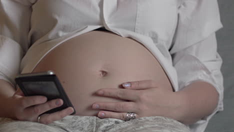 Mujer-Embarazada-Relajándose-Con-Un-Teléfono-Inteligente