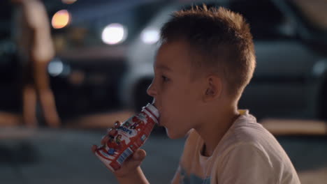 Boy-drinking-yoghurt-outdoor-at-night