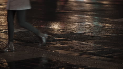 Gente-Cruzando-La-Calle-Caminando-Sobre-Camino-Mojado-En-La-Ciudad-De-Noche