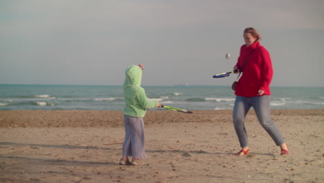Kid-and-mom-playing-beach-tennis-near-the-sea
