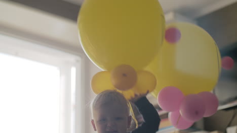 Verspieltes-Kleines-Mädchen-Mit-Luftballons-Im-Kinderbett