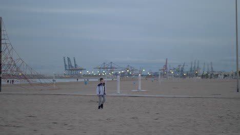 Young-boy-walking-on-the-beach-on-a-cold-day