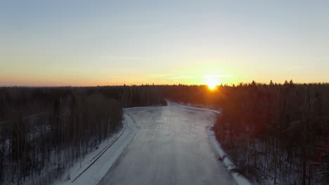 Aerial-view-of-winter-forest-and-frozen-river-at-sunrise