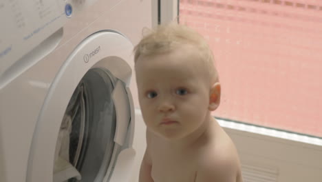 Lovely-baby-girl-is-curious-about-washing-machine