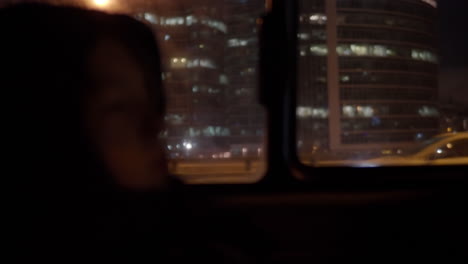 Kinderautopassagier-Gegen-Das-Fenster-Mit-Nachtblick-Auf-Die-Stadt