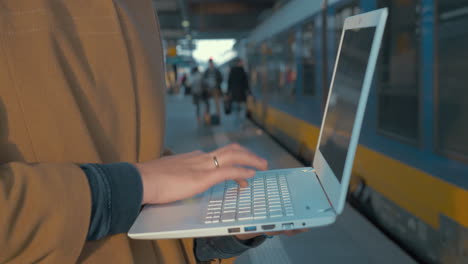 Woman-using-laptop-by-train-at-the-station