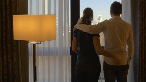 Young-couple-hugging-and-looking-out-the-window