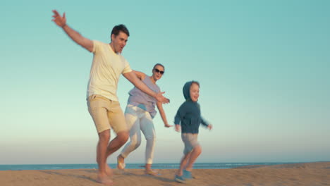 Glückliche-Dreiköpfige-Familie,-Die-Am-Strand-Spielt