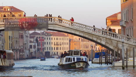 People-crossing-the-bridge-water-trams-sailing-beneath