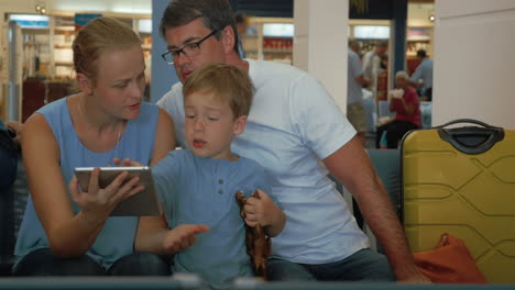 Padres-E-Hijos-Usando-Tableta-Digital-En-El-Aeropuerto